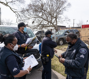 (Clockwise left to right) Detroit Police Department Neighborhood Police Officers Marcia Williams, Dan Robinson and Eric Hill gather with Sergeant Charles Spruce before handing out gun safety information and gun locks while going door-to-door along Fenelon Street on Detroit's east side on Thursday, March 25, 2021.