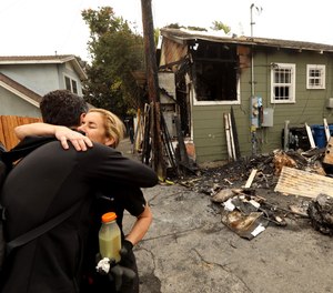 Courtney Gillenwater, facing, receives a hug of support from Brian Averill, with Venice Boardwalk Action Committee, in front of her fire damaged home. The fire is under investigation but residents in the neighborhood believe it may have been set by new homeless in the area.