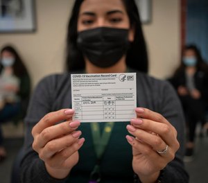 Receptionist Maribel Hidalgo displays her vaccination card after receiving the Moderna COVID-19 vaccine at the Virginia Garcia Memorial Health Center in Hillsboro, Oregon, on January 8, 2021.