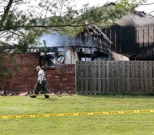 A firefighter walks by three destroyed town homes in the 400 block of Cardin Place in Eagleville on Thursday. Investigators say the blaze started inside one of the homes shortly before 1 p.m.