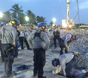 Members of Ohio Task Force 1 survey an area where debris has recently been removed during a mission at the Champlain Towers South condo building in Surfside, Florida. The Ohio team arrived on July 2 and completed its mission July 13
