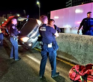 Officer Greg Rose holding a 14-month-old boy rescued from a car crash on the George Washington Bridge early Wednesday morning on August 4, 2021.