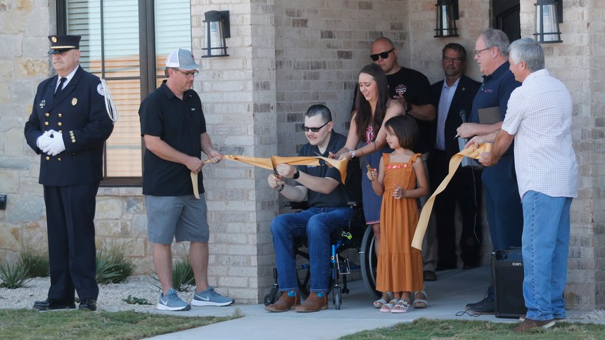 Lubbock Fire Rescue Firefighter Matt Dawson and wife, Chanda, and his 7-year-old daughter, Preslee, cut the ribbon to their new home. He and his family were presented a new home on Richmond Avenue.