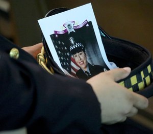 A police officer holds an image of Officer Ella French in his hat during her funeral service on Aug. 19, 2021, at St. Rita of Cascia Shrine Chapel.