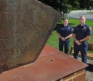 Tallmadge firefighter Kyle Morrow, left, and Deputy Fire Chief Ben Stasik pose for a photo in Tallmadge next to a chunk of steel beam from the World Trade Center.