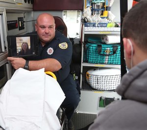 Firefighter/paramedic Adam Lovell, left, holds a tablet showing Dr. Holli Hill via the Akron Fire Department's new telehealth program during a demonstration with firefighter/paramedic Dan Hilton portraying the patient Tuesday, Sept. 14, 2021 in Akron, Ohio.