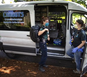CAHOOTS emergency medical technician Summer Johnson, left, and crisis worker Amy May stop by Monroe Park in Eugene at the end of their 12-hour shift. The Eugene-based mobile crisis intervention program of White Bird Clinic has become a nationwide model as cities search for ways to handle calls for service without involving the police.