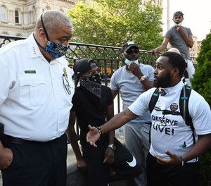 Baltimore Police Commissioner Michael Harrison listens to a question from, on right, Wesley Hawkins, of The Nolita Project, at a rally at City Hall to remember George Floyd and other African Americans killed by police and demand change.