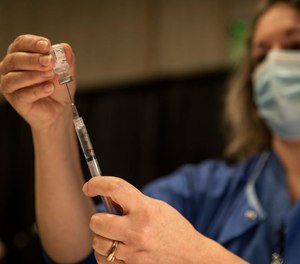 Kelly Beckley, R.N., preps vials of the Pfizer COVID-19 vaccine to be administered to teachers and educators at The Oregon Convention Center on January 27, 2021, in Portland.