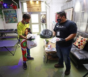 Diamond Mendoza, left, receives healthcare items from Program Manager Christian Diaz at the drop-in center of their location in Skid Row in September of 2021.