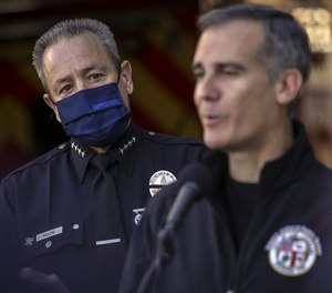 LAPD Chief Michel Moore, left, watches as Mayor Eric Garcetti addresses a press conference on Thursday, Jan. 6, 2022 in Los Angeles, Calif.