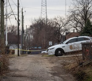 Homicide investigators survey the scene around a home in Indianapolis on Sunday, March 14, 2021, after four people, including a child, were found dead.