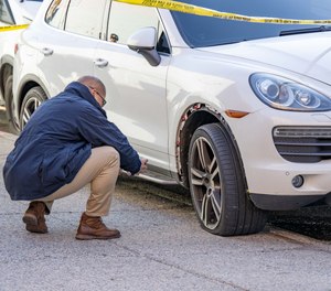 An officer inspects a blown tire after an NYPD officer opened fire at a stolen Porsche on Sunday, April 10, 2022.