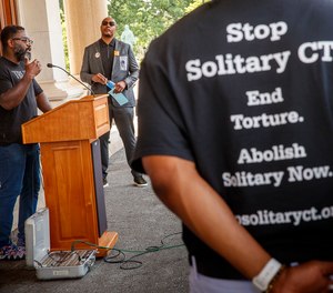 Caron Butler (middle) listens to speaker Reginald Dwayne Betts talk about his experiences in solitary confinement during a press conference at the Connecticut State Capitol on June 7, 2021.
