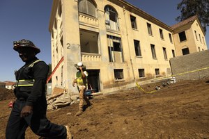 Construction workers walk past Building 207, which is being refurbished as housing for veterans on the Veteran Affairs West L.A. campus in Los Angeles on June 23. This is the collective's first project. The 60-unit building for senior veterans and their families and is scheduled to open this fall.