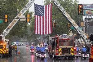 The body of Lt. Sean Williamson travels past an American flag hung from ladder trucks 14 and 19 outside Ladder 18 and Engine 59. Fire Station Ladder 18, Engine 59 is where Williamson was stationed. Williamson died in the line of duty after a fire-damaged building collapsed in Philadelphia on June 18.