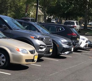 A line of parked cars all display front license plates as required by New Jersey law. Two bills in the legislature and a petition call for the state to drop the requirement for a front license plate.