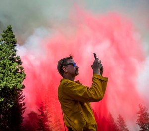 Travis Thane, U.S. Department of Agriculture division chief, takes video of a tanker after it drops fire retardant on the Mosquito Fire near Foresthill on Tuesday.