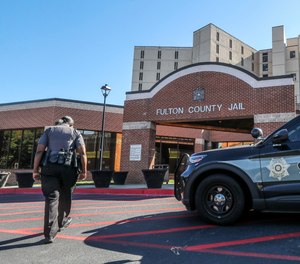 A Fulton County sheriff's deputy walks towards the entrance to the Fulton County Jail on Friday, Sept. 23, 2022. The county's jail facilities are severely overcrowded.
