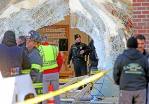 Hingham police officers and firefighters survey a mass casualty scene where a car drove into the front of an Apple Store on Nov. 21.