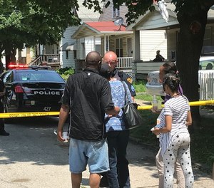 Family members speak with a Cleveland police officer outside a homicide scene in the Slavic Village neighborhood.