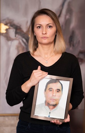 Enika Frasheri Sopiqoti is pictured with a portrait of her father, Genci Frasheri, on Dec. 9, 2022 in Queens, New York. The family filed a $20 million notice of claim Monday against the city.