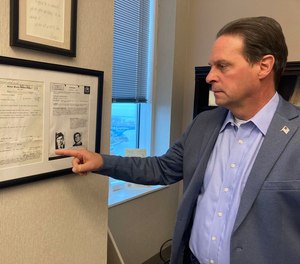 U.S. Marshal Peter Elliott stands with a warrant for fugitive Ted Conrad that is signed on behalf of his father who started investigating the case decades earlier.