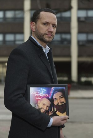 Phillip Liming holds a picture of himself (left) with friend and former roommate Leonardo Guerrero, while standing outside their former residence. Chicago Fire Department paramedics transported him to a nearby hospital after he was found outside the building. Guerrero died.