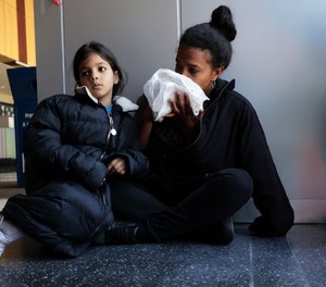 Venezuelan migrants Karen Malave and daughter Avril Brandelli, 7, eat food left by a volunteer on their seventh day of waiting inside Chicago's 16th District police station.