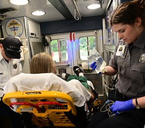 Paramedic Kyle Bayens, left, and EMT Emilie Thurston, right, work on a patient inside their ambulance before transporting him to a hospital on May 16, 2023, in Denver. The patient called 911 because he was vomiting blood. In a typical year, Denver Health says their paramedics respond to more than 100,000 calls and take more than 70,000 patients to the hospital.