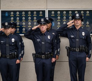 Officers salute during the playing of the National Anthem during a ceremony at LAPD Headquarters in Los Angeles.