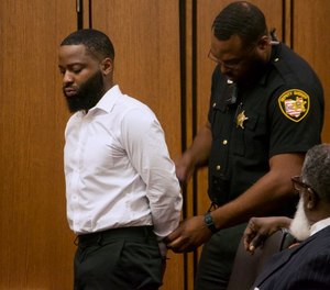 A Cuyahoga County sheriff's deputy places former East Cleveland police officer Alfonzo Cole in handcuffs after a judge sentenced Cole to 30 months in prison for robbing four motorists during his time on the force.