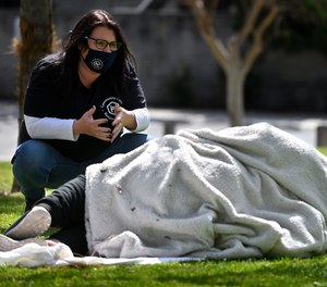 Erin Hishmeh of City Net’s Community Care Response Team in Anaheim talks to a woman in La Palma Park in Anaheim who later agreed to accept the help of a shelter.