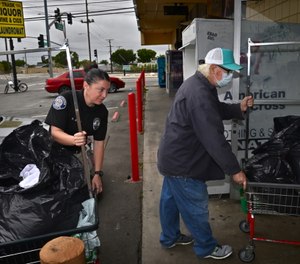 Homeless Liaison Officer Nicole Brown helps Philip bring his laundry to the laundromat.