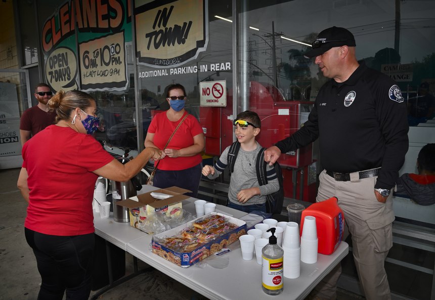 Helping at the table are volunteer Linda Middendof, Aisaiah Perez, 7, and his dad, Westminster Police Department Homeless Liaison Officer Roland Perez, right.