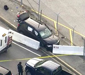 In this image made from video and provided by WUSA TV-9, authorities investigate the scene of a shooting at Fort Meade, Md. on Wednesday, Feb. 14, 2018. A suspect has been held, taken from the black SUV that stopped at barrier after a shooting outside National Security Agency. (WUSA TV-9 via AP)