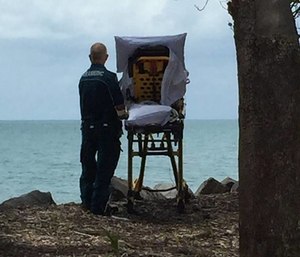 Paramedic Graeme Cooper stands next to a patient’s gurney and looking out at the ocean. (Photo/Facebook)