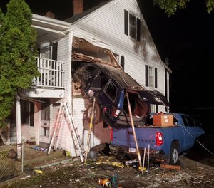 At about 1:30 a.m., the East Great Plain Volunteer Fire Company arrived at the scene of the house at 665 West Thames St. to find a dark blue SUV stuck nose-first in the upper story of the house, perched on the bed of a pickup truck parked in front.