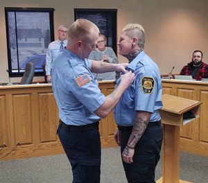 Acting Lt. John Krueger pinning on firefighter-EMT Erica Kostichka's badge. She completed her 18-month probationary period in April 2022.
