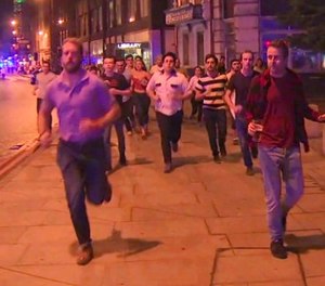 In this image taken from video footage, people run from the scene of attack, alongside a man strolling holding a pint of beer, right, in London, late Saturday, June 3, 2017. (Sky news via AP)