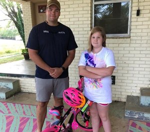 Deputy Justin Butcher, left, long with representatives with a local Walmart, replaced the girl's bike and got her a new helmet.