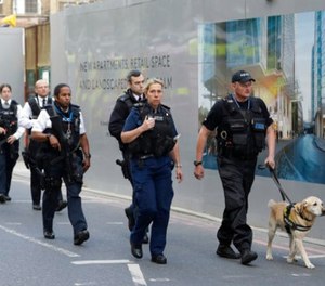 A group of armed British police officers walk with a detection dog after an attack in the London Bridge area of London, Sunday, June 4, 2017. (AP Photo/Matt Dunham)