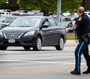 An Omaha police officer points his rifle in the direction of a vehicle headed eastbound on Cuming Street driven by an inmate who escaped from the Pottawattamie County jail in Council Bluffs, Iowa, and carjacked a Nissan Sentra, Monday, May 1, 2017, in Omaha, Neb.