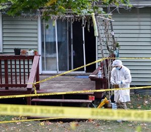 Police investigate the backyard of a home where they say four people have been found slain in Guilderland, N.Y., on Wednesday, Oct. 8, 2014.