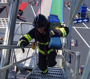 Starting at the base of the tower, competitors race up a flight of stairs carrying a 42-lb. hose pack.