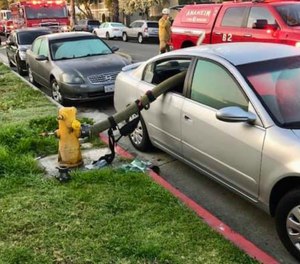 Firefighters broke both back passenger windows of the parked car and snaked the hose through, and eight people were eventually evacuated from the house fire. (Photo/Anaheim Fire & Rescue)