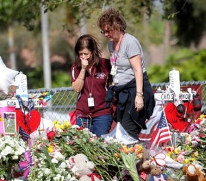 Margarita Lasalle, a bookkeeper and Joellen Berman, a guidance data specialist, look at a memorial Friday, Feb. 23, 2018 as teachers and school administrators returned to Marjory Stoneman Douglas High School for the first time since 17 victims were killed in a mass shooting at the school, in Parkland, Fla.