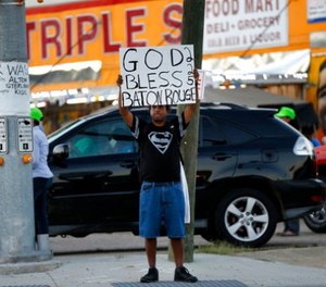 Everett Matthews of Baton Rouge, holds up a sign outside the Triple S Food Mart, where Alton Sterling was killed last year, in Baton Rouge, La., Tuesday, May 2, 2017.