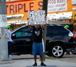 Everett Matthews of Baton Rouge, holds up a sign outside the Triple S Food Mart, where Alton Sterling was killed last year, in Baton Rouge, La., Tuesday, May 2, 2017.