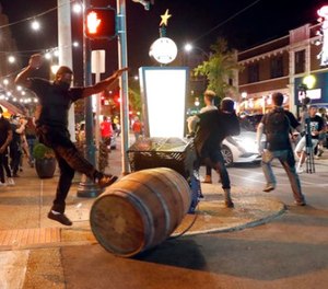 Protesters overturn trash cans as police try to clear a violent crowd Saturday, Sept. 16, 2017, in University City, Mo.